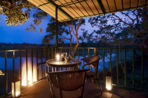 a table and chairs on a balcony with lights at Neem Tree House in Kirinda