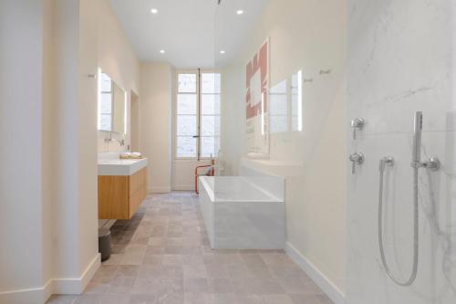une salle de bain blanche avec une baignoire et un lavabo dans l'établissement Chic 7th Elegance, à Paris