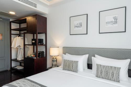 a bedroom with a bed with white sheets and pillows at Souphattra Hotel Luang Prabang in Luang Prabang