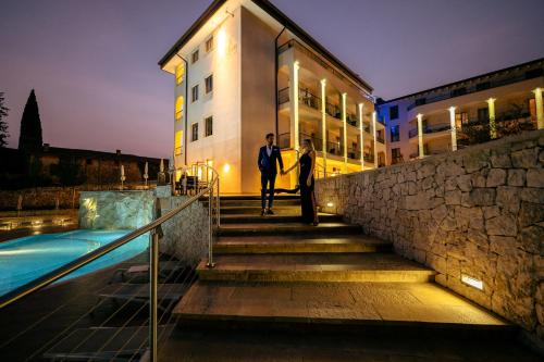 deux personnes debout dans les escaliers à côté d'un bâtiment dans l'établissement Villa Luisa Resort & Luxury Apartments, à San Felice del Benaco