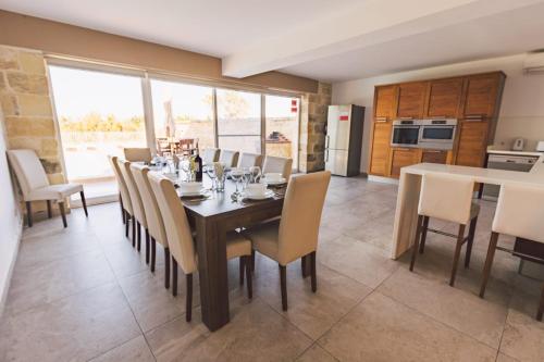 a dining room with a table and chairs and a kitchen at Villa Mercury in Żejtun