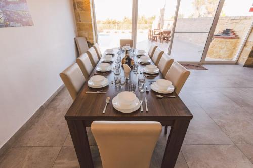 a long wooden table with white plates and silverware at Villa Mercury in Żejtun