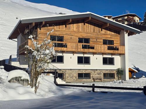 a wooden building with a balcony in the snow at Ferienhaus Evelyn in Tux