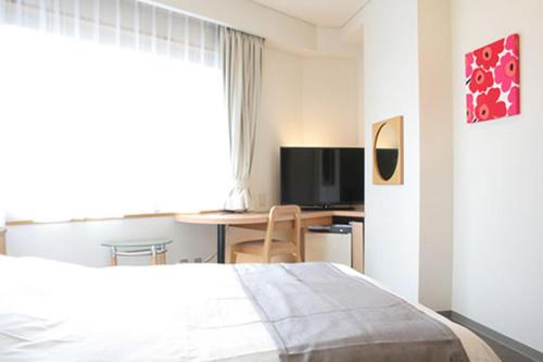 Dormitorio con cama, escritorio y TV en Hotel Estacion Hikone, en Hikone