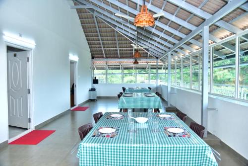 马迪凯里Coorg Balaji Palace Homestay Madikeri的用餐室设有绿色桌椅和窗户。