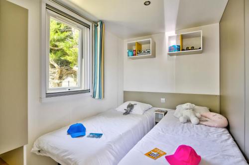 - 2 lits dans une petite chambre avec 2 fenêtres dans l'établissement Domaine Résidentiel de Plein Air Le Bois d'Amour, à Quiberon