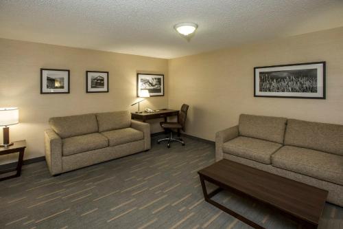 a hotel room with two couches and a desk with a table at Holiday Inn Lethbridge by IHG in Lethbridge