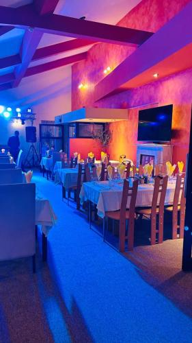 a dining room with tables and chairs and a tv at Vila Condor in Poiana Brasov