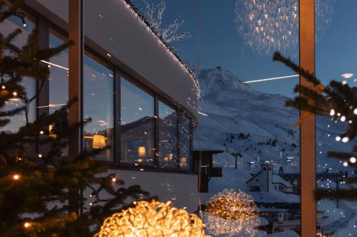 a window with christmas lights and a snowy mountain at SKI - GOLF - WELLNESS Hotel Riml in Hochgurgl
