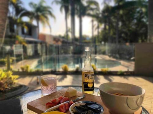 a table with a bottle of beer and a bowl of food at Noosa Sound - 2brm Townhouse in Noosaville