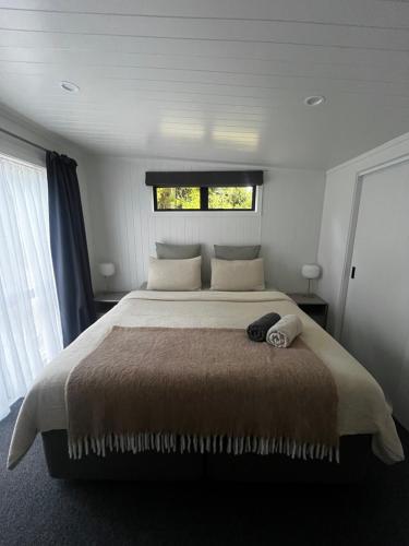 a bedroom with a large bed with a window at Pond Road Park - Raglan in Raglan