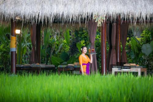 a woman standing in a field of tall grass at Saren Indah Hotel in Ubud