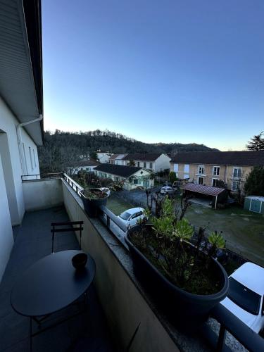 a balcony with a table and some plants on it at LE PAISIBLE - Parking gratuit - Entrée ville in Jurançon