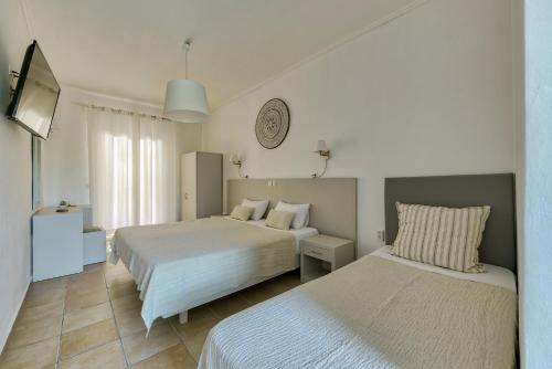 a hotel room with two beds and a television at Ecoresort Hotel Zefyros in Ayios Kirikos
