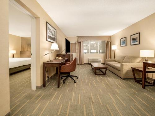 a hotel room with a couch and a desk and a bed at Holiday Inn Lethbridge by IHG in Lethbridge