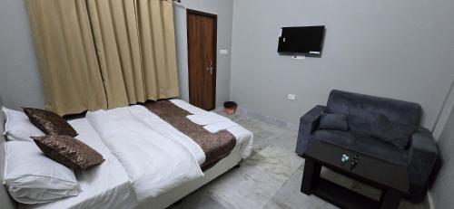AyodhyaにあるSUSHMA Residencyのベッドと椅子とテレビのある寝室