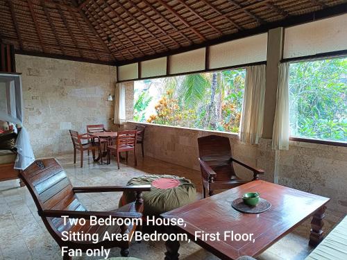 ein Esszimmer mit Tischen und Stühlen und einem großen Fenster in der Unterkunft Guci Guesthouses in Ubud