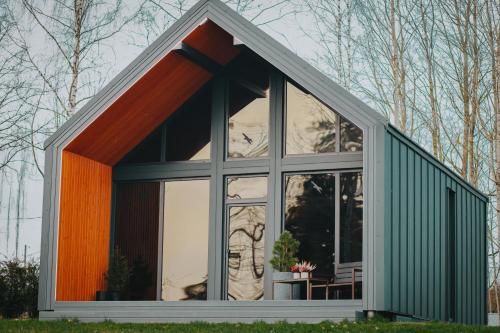 a small house with a large window at Sniegi design cabin with sauna in Madona