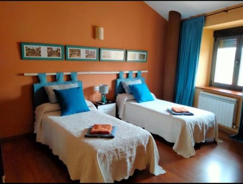 a bedroom with two beds with blue pillows at Casa Rural El Montaraz de Gema in Gema