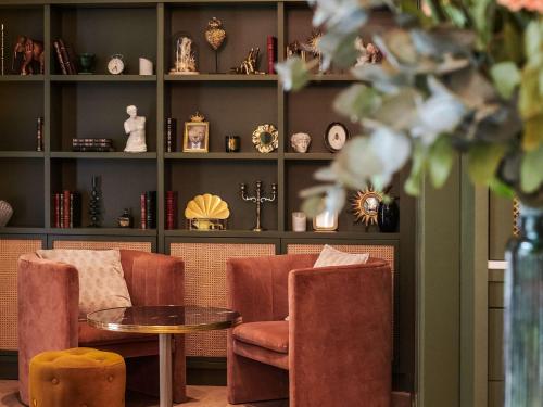 a room with two chairs and a table and shelves at Square Lodge Hotel La Roche sur Yon - Handwritten Collection in La Roche-sur-Yon