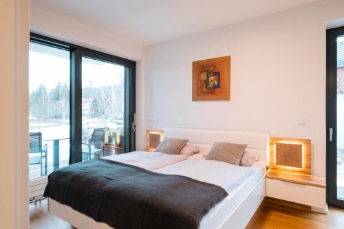a bedroom with a large bed and a large window at MOLO LIPNO RESIDENCE in Lipno nad Vltavou