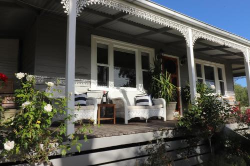 une maison avec des chaises en osier blanc sur une terrasse couverte dans l'établissement Bylands Cottage Historic Home - Tambo river views and pet friendly, à Swan Reach