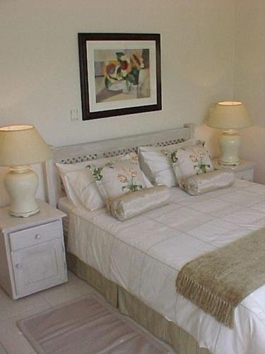 a bedroom with a white bed with two lamps at Luxury 4 bed villa in San Lameer golf beach estate in Southbroom