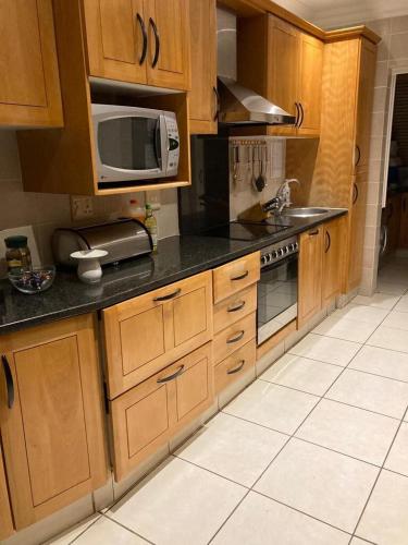 a kitchen with wooden cabinets and a microwave at Luxury 4 bed villa in San Lameer golf beach estate in Southbroom