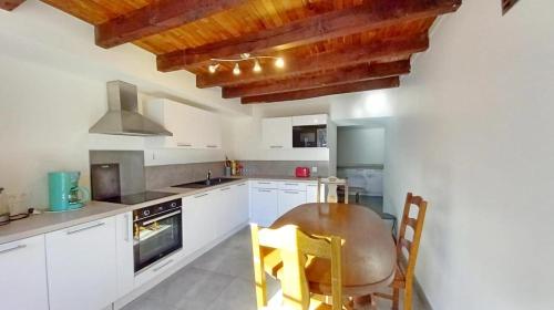 une cuisine avec des armoires blanches et un plafond en bois dans l'établissement Gite agréable en Creuse, à Saint-Georges-la-Pouge
