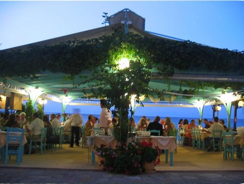 un grupo de personas sentadas en mesas en un restaurante en Poseidon Studios, en Kokkari