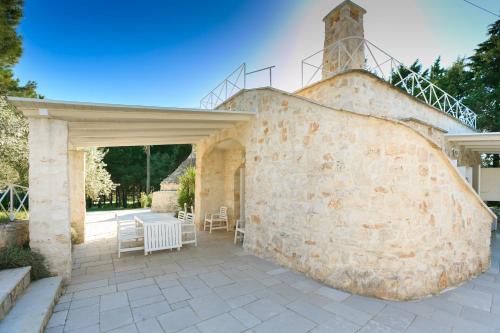 a stone wall with a table and chairs on a patio at Le Dimore di Trulli Mandorlo con piscina esclusiva in Putignano