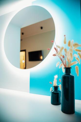 two black vases with flowers on a table in front of a mirror at Penelope's Suite&Spa con parcheggio privato in Como