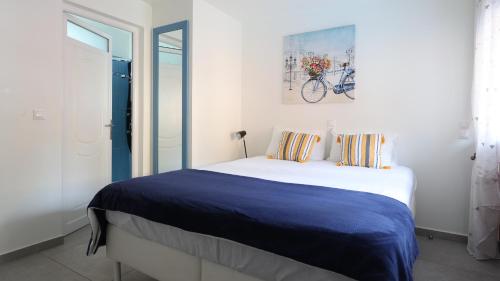a white bedroom with a large bed with blue sheets at The Bordeaux Door in Aegina Town