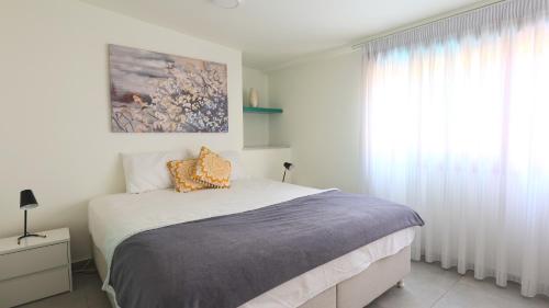 a white bedroom with a bed and a window at The Bordeaux Door in Aegina Town