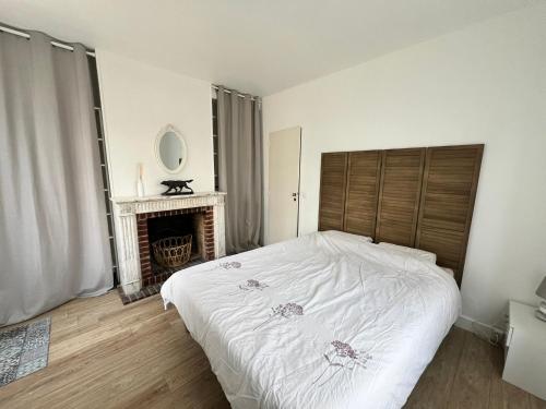 - une chambre avec un lit blanc et une cheminée dans l'établissement Un secret bien gardé, à Fontenay-le-Fleury