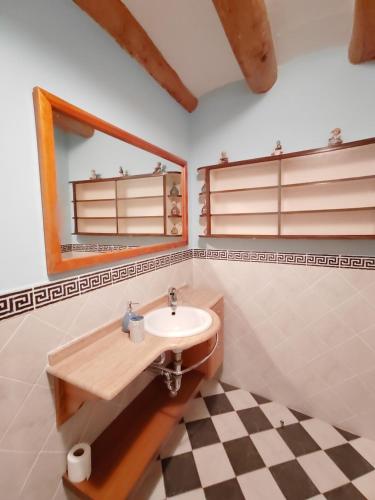 a bathroom with a sink and a mirror and a checkered floor at La Alcoba de Becquer in Vera de Moncayo