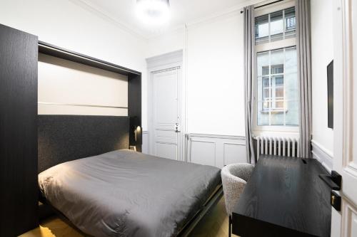 une chambre avec un lit, un bureau et une fenêtre dans l'établissement Appartement neuf et luxueux climatisé à Paris 17, à Paris