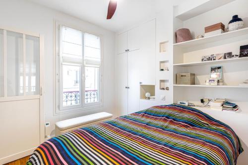 - une chambre avec un lit et une couverture rayée colorée dans l'établissement GuestReady - Parisian style home by la Bastille, à Paris
