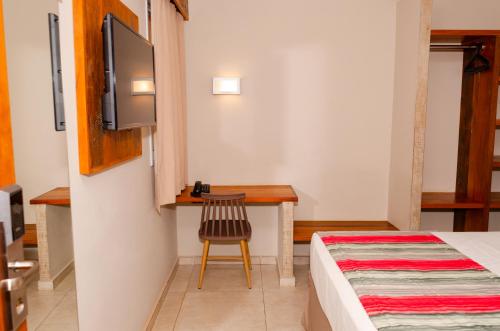 a bedroom with a bed and a desk and a tv at Meu Hotel Boituva in Boituva