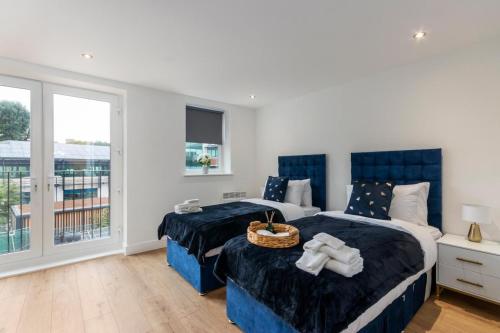 ein Schlafzimmer mit zwei Betten und einem Balkon in der Unterkunft Deluxe 2-Bedroom Saarb Apartment, Leatherhead in Leatherhead