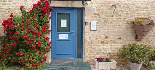 a blue door on a brick building with red flowers at Au Petit Pressoir in Givry
