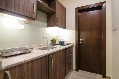 a kitchen with a sink and a wooden door at 46 Serviced Apartments in Amman