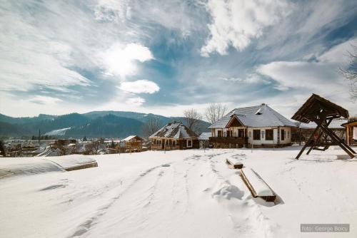 a snow covered yard with houses and buildings at Pension La Roata in Gura Humorului