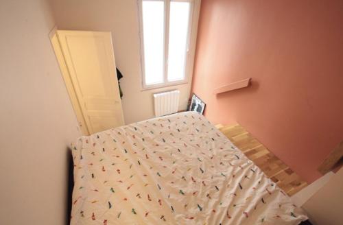 une chambre avec un lit avec une couette et une fenêtre dans l'établissement Sweet little flat in Montmartre, à Paris