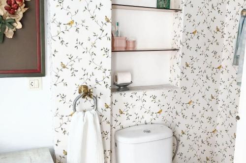 a bathroom with a toilet and flowers on the wall at Spacious house with terrace and balcony in A Coruña in A Coruña