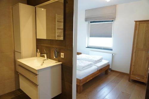 two pictures of a bathroom with a sink and a bed at Kustverhuur, Appartement aan Zee, Port Scaldis 01061 in Breskens