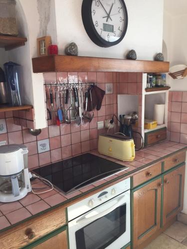a kitchen with a clock on the wall above a stove at La Léinade in Île dʼAix