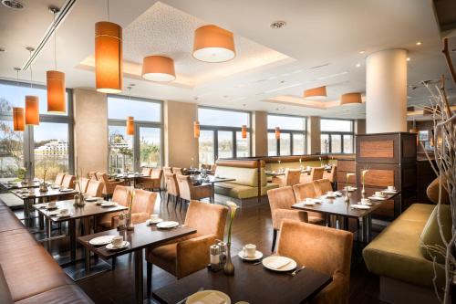 a restaurant with tables and chairs and windows at elaya hotel hamburg finkenwerder in Hamburg