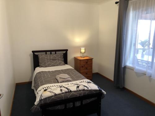 a bedroom with a bed and a dresser and a window at The Cozy Penguin with Sea Views in Cooee