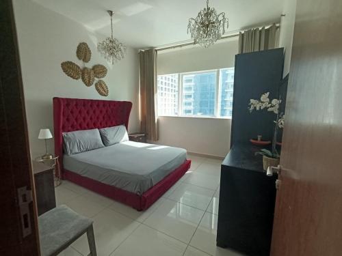 a bedroom with a bed with a red headboard and a window at In the heart of Dubai in Dubai